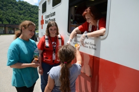 June 29, 2016. Clay, West Virginia. Red Cross volunteer Marie Loyons serves food to Loretta King and her eight-year-old daughter Byany King with Red Cross employee Mary Williams in the background. The Red Cross Emergency Response Vehicle is at Clay High School at a community relief distribution point to assist flood victims from Clay, West Virginia. The vehicle contains 300 hot meals of chicken dumplings and mixed vegetables, along with pudding or a cookie for desert. Photo by Daniel Cima for the American Red Cross